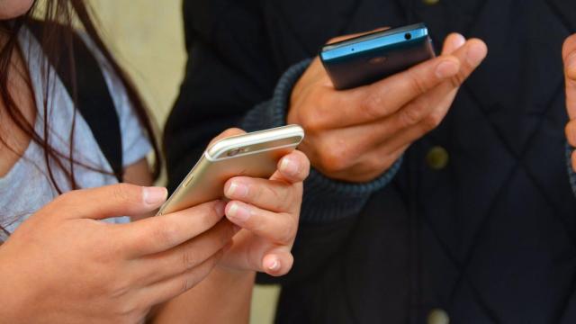 Jóvenes usando un teléfono movil.