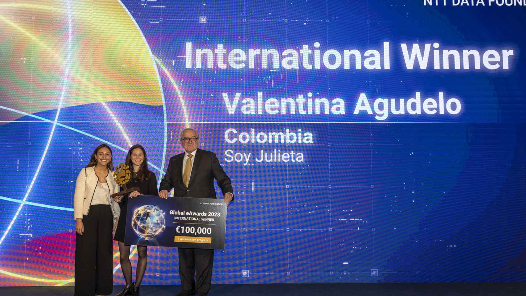 Cristina García y Valentina Agudelo, fundadoras de Soy Julieta, posan con el galardón de los Global eAwards y el presidente de NTT DATA FOUNDATION, Roberto Dañino.