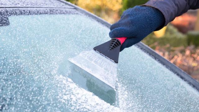 Una persona utilizando la rasqueta para limpiar el hielo del parabrisas