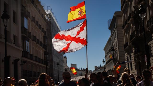 Varias personas portan una bandera de España y otra con la cruz de Borgoña durante una manifestación.