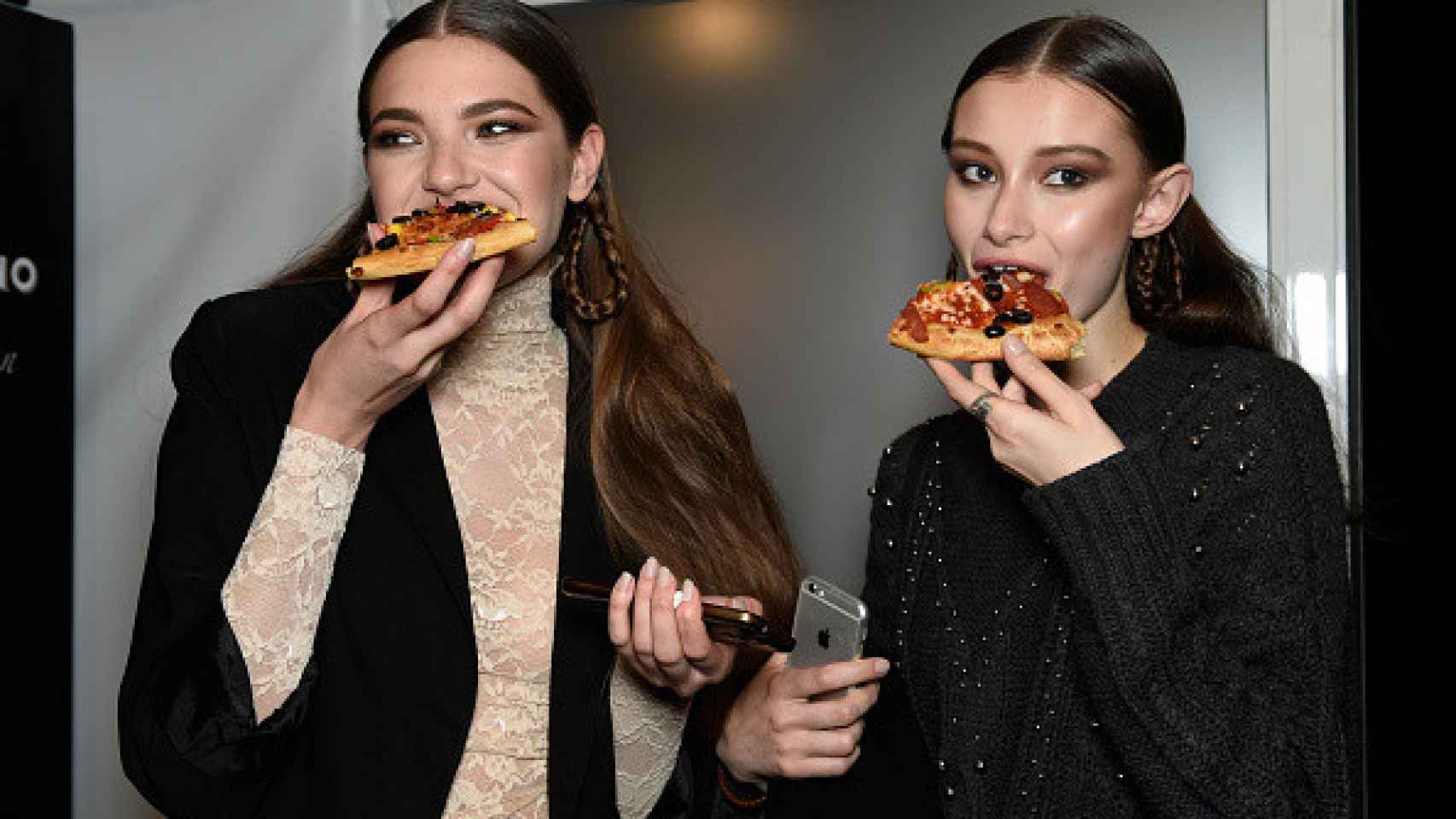 Dos modelos tomando pizza.