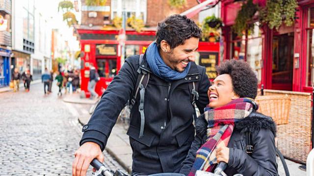 Una pareja montando en bicicleta por una calle de una ciudad de Irlanda