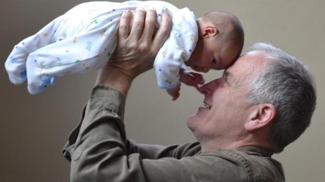 Un abuelo sostiene a su nieto en brazos.