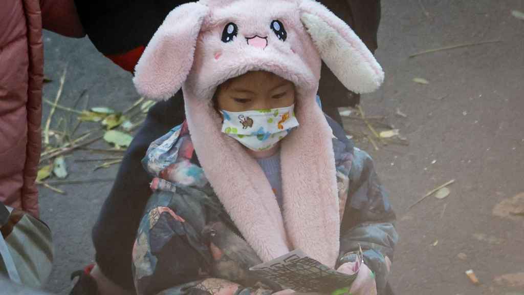 Una niña con mascarilla a la salida del colegio en Pekín este 23 de noviembre de 2023